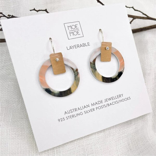 Pair of hoop earrings with wooden accents on a Moe Moe branded card.