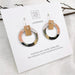 Pair of hoop earrings with wooden accents on a Moe Moe branded card.
