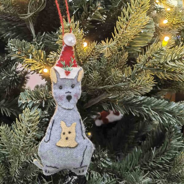 Decorative Christmas ornament of a kangaroo with a Santa hat on a Christmas tree.