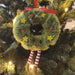 Decorative ornament shaped like a wreath with a face, hanging on a Christmas tree.