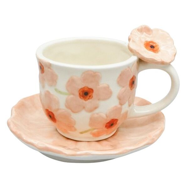 Ceramic cup with floral design on a matching saucer, featuring a decorative flower on the handle.